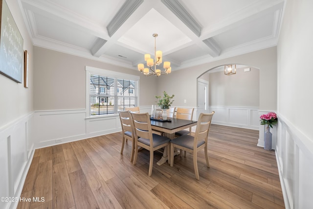 dining space with a chandelier, beam ceiling, and light wood-style floors