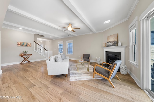 living area with light wood-type flooring, stairs, baseboards, and beam ceiling