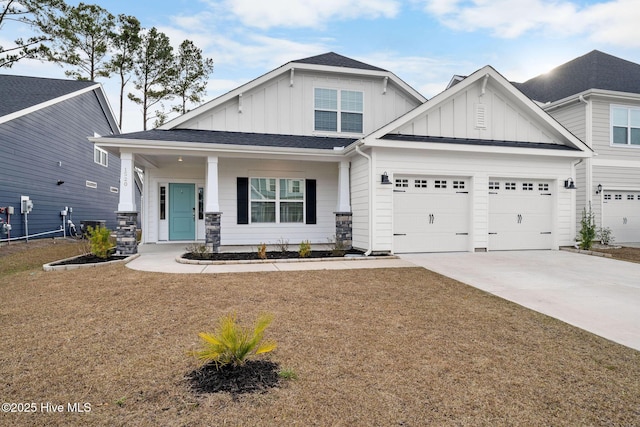 craftsman house with a garage, concrete driveway, covered porch, a front lawn, and board and batten siding