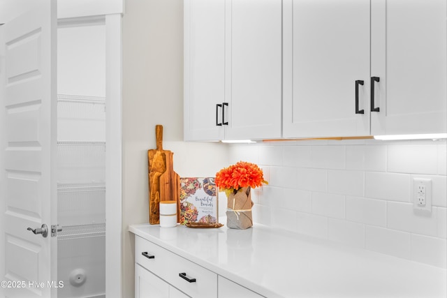 interior details featuring light countertops, tasteful backsplash, and white cabinets