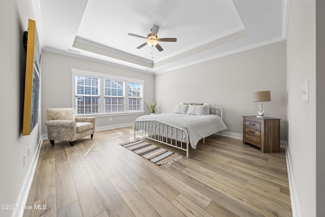 bedroom with a tray ceiling, crown molding, visible vents, light wood-type flooring, and baseboards