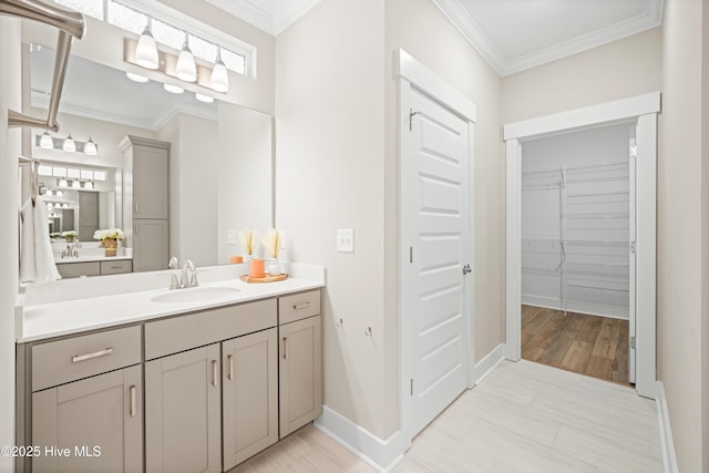 bathroom with a spacious closet, ornamental molding, vanity, and baseboards