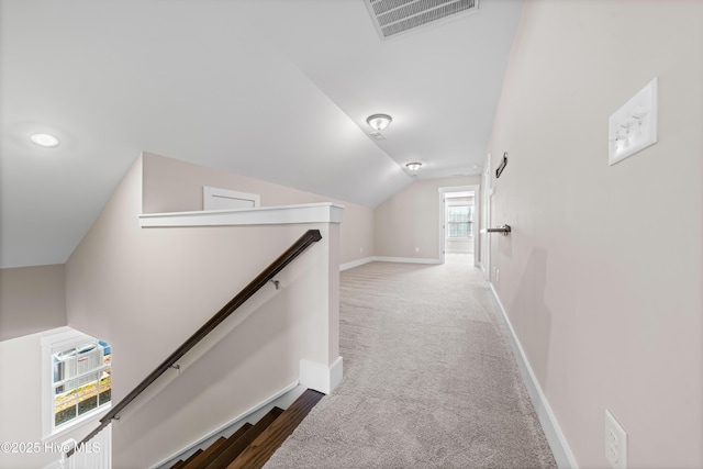 hall featuring lofted ceiling, visible vents, carpet flooring, an upstairs landing, and baseboards