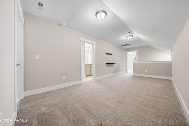 unfurnished living room featuring light carpet, lofted ceiling, and visible vents