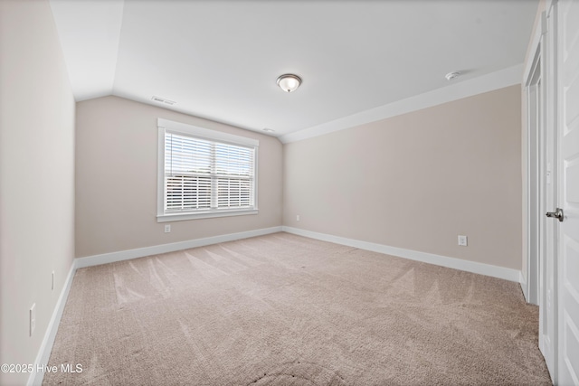 empty room with light carpet, baseboards, visible vents, and vaulted ceiling