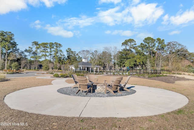 view of community with an outdoor fire pit, fence, and a patio