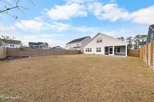 rear view of property featuring a yard, a patio, a fenced backyard, and a sunroom