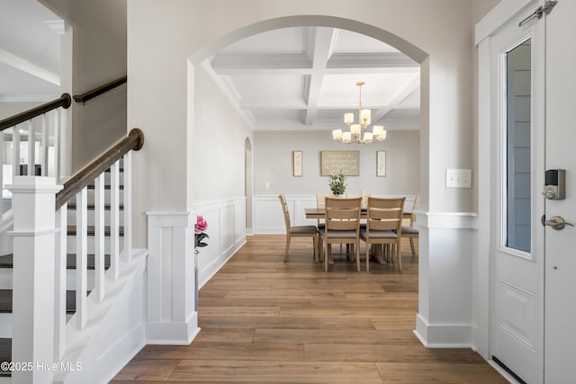 dining area with coffered ceiling, a wainscoted wall, wood finished floors, stairs, and beam ceiling