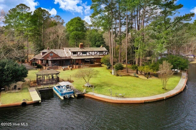 back of property featuring a water view, a lawn, and boat lift