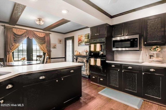 kitchen with black appliances, dark cabinetry, and light countertops