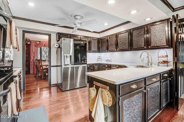 kitchen with ornamental molding, stainless steel fridge, a sink, and light wood finished floors