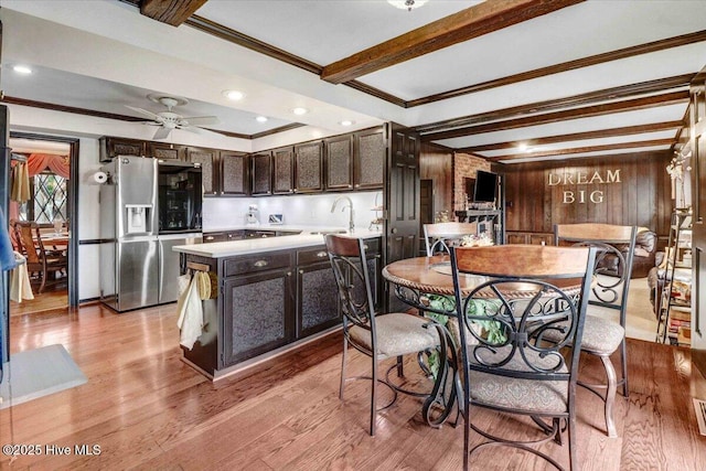 kitchen with dark brown cabinets, light countertops, light wood-type flooring, stainless steel refrigerator with ice dispenser, and beamed ceiling