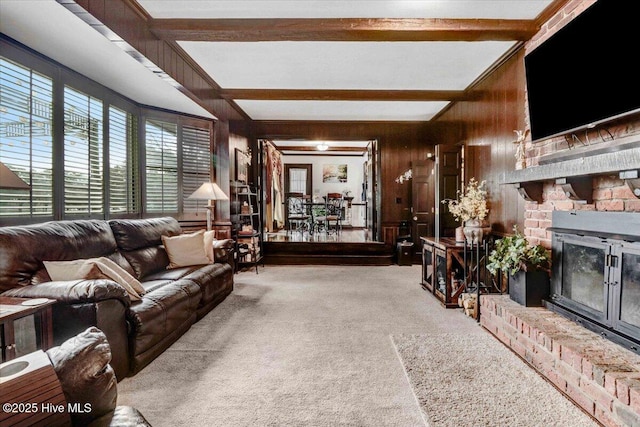 living room featuring carpet floors, a brick fireplace, wooden walls, and beamed ceiling