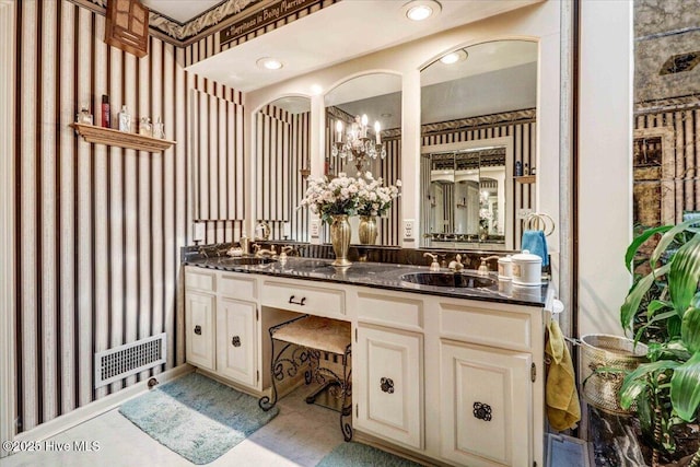 full bath with a chandelier, double vanity, a sink, and visible vents