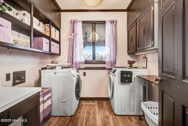 laundry area featuring dark wood-style floors, ornamental molding, cabinet space, and washer and dryer