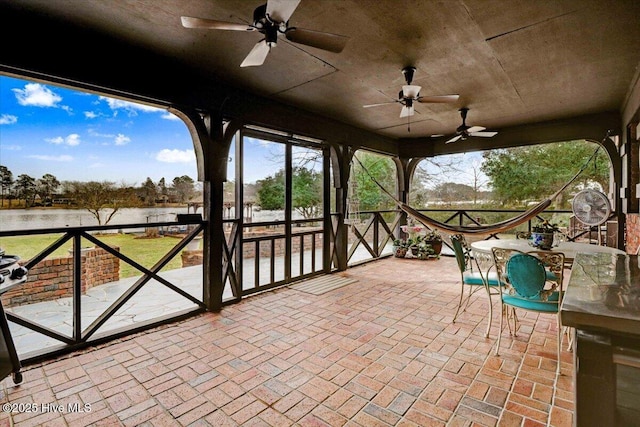 view of patio / terrace featuring outdoor dining space, a water view, and ceiling fan