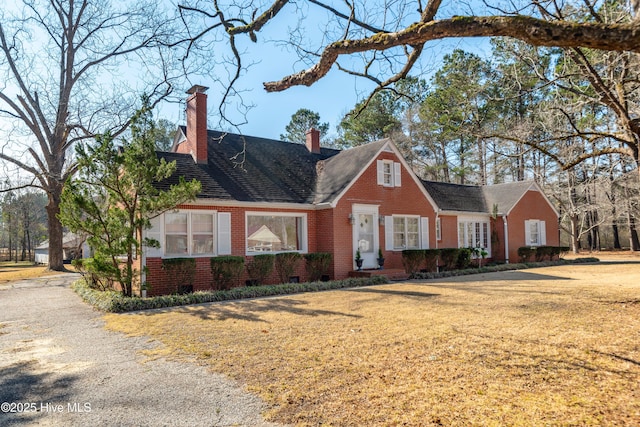 cape cod-style house with crawl space, a chimney, a front lawn, and brick siding