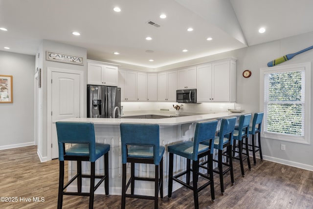 kitchen with stainless steel appliances, light countertops, visible vents, white cabinetry, and wood finished floors