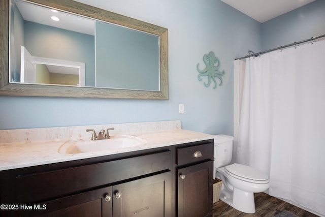 bathroom featuring toilet, a shower with shower curtain, wood finished floors, and vanity