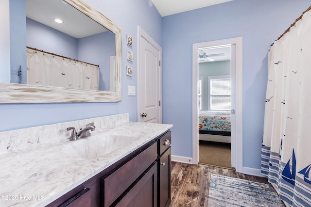 bathroom featuring ceiling fan, connected bathroom, vanity, wood finished floors, and baseboards