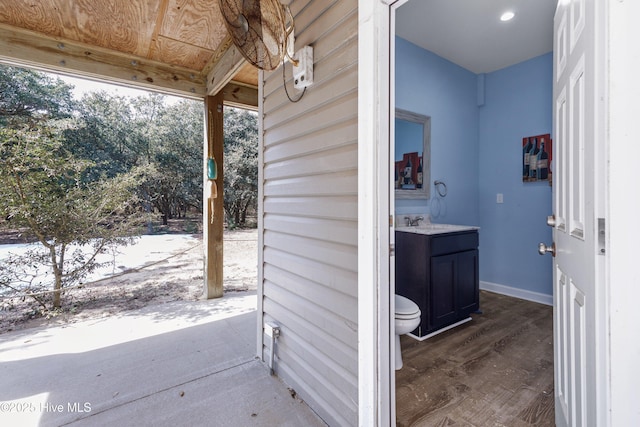 exterior space with wood finished floors, vanity, toilet, and baseboards