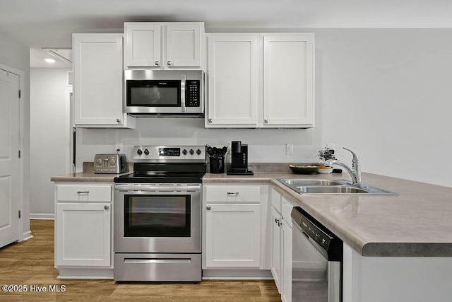 kitchen featuring appliances with stainless steel finishes, white cabinets, and a sink