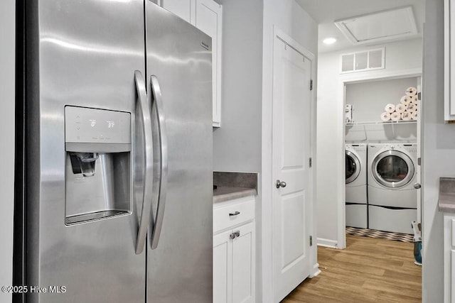 interior space with white cabinets, stainless steel fridge, visible vents, and washer and dryer