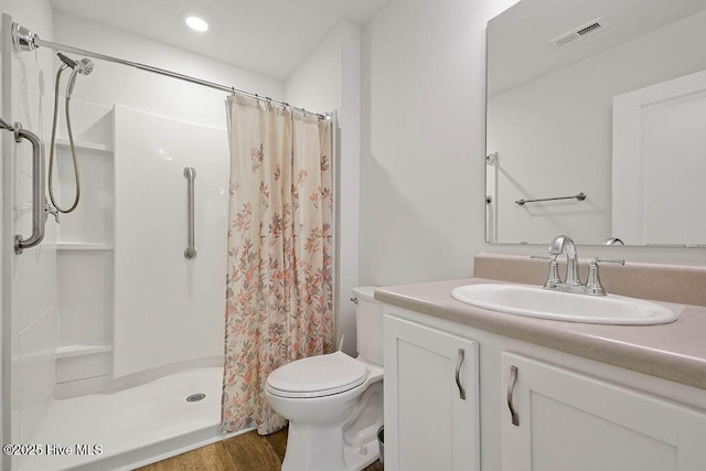 bathroom with toilet, a stall shower, vanity, and visible vents