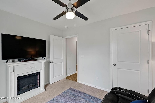 living area featuring carpet, a fireplace, baseboards, and ceiling fan