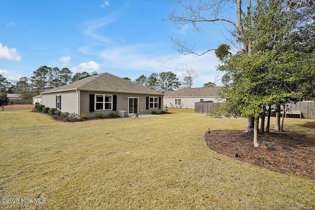 rear view of property featuring a lawn, fence, and central air condition unit