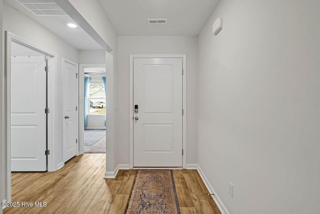 doorway with light wood finished floors, baseboards, and visible vents