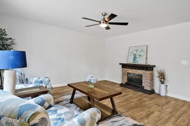 living room with a ceiling fan, a fireplace, baseboards, and wood finished floors