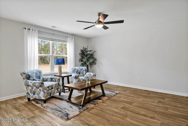 living area with wood finished floors, visible vents, and baseboards