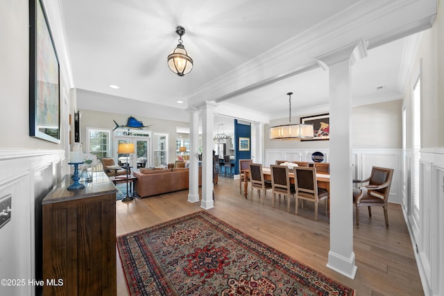 living area featuring crown molding, ornate columns, and wood-type flooring