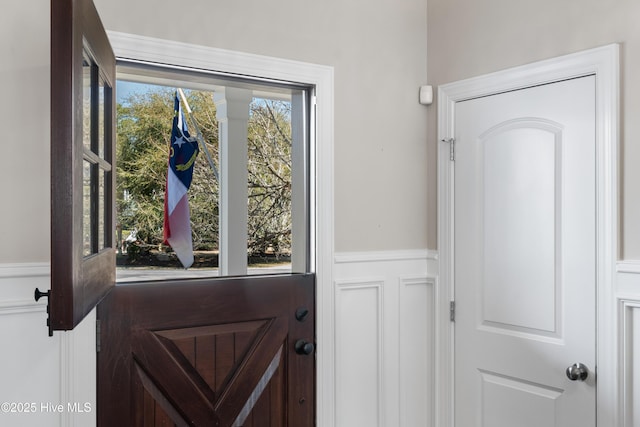 doorway to outside featuring a wainscoted wall