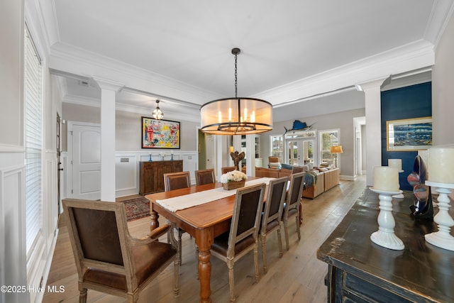 dining room with wainscoting, light wood-style floors, and decorative columns