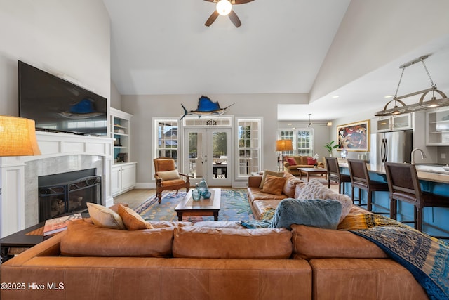 living area with wood finished floors, high vaulted ceiling, ceiling fan, and a premium fireplace