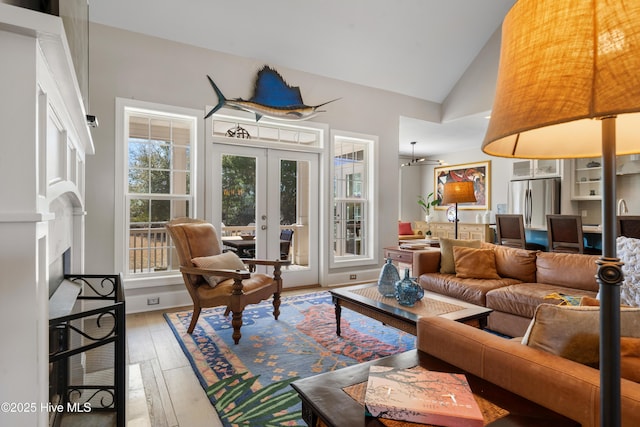 living area with french doors, lofted ceiling, hardwood / wood-style floors, and a fireplace