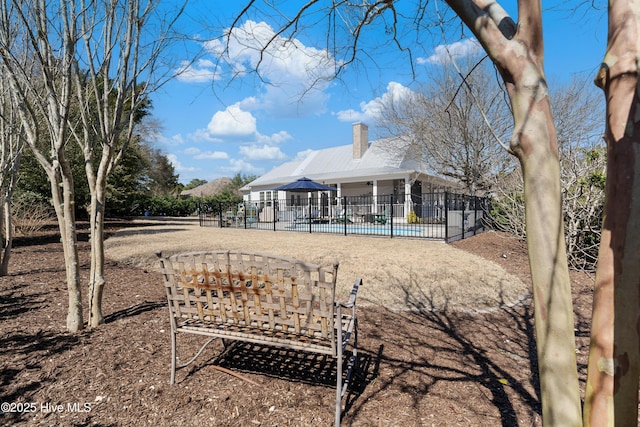 back of house featuring a fenced in pool, a patio, a chimney, and fence