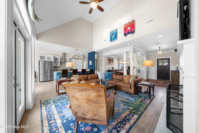 living room with visible vents, high vaulted ceiling, light wood-style flooring, a ceiling fan, and ornamental molding