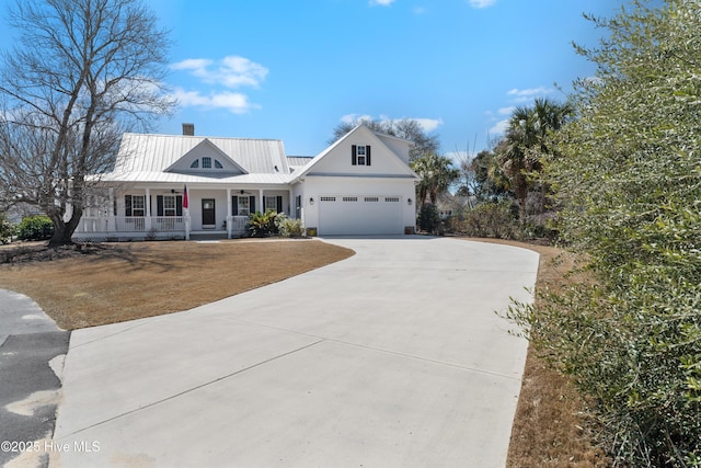 view of front of home featuring an attached garage, covered porch, a chimney, metal roof, and driveway