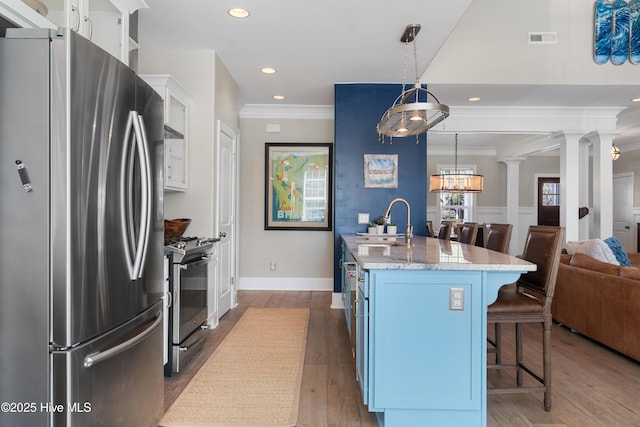 kitchen featuring visible vents, decorative columns, appliances with stainless steel finishes, a kitchen breakfast bar, and a sink