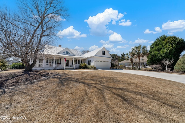 view of front of home featuring driveway, covered porch, a chimney, a front lawn, and metal roof