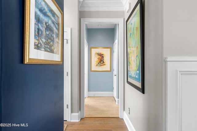 hallway with ornamental molding, baseboards, and wood finished floors