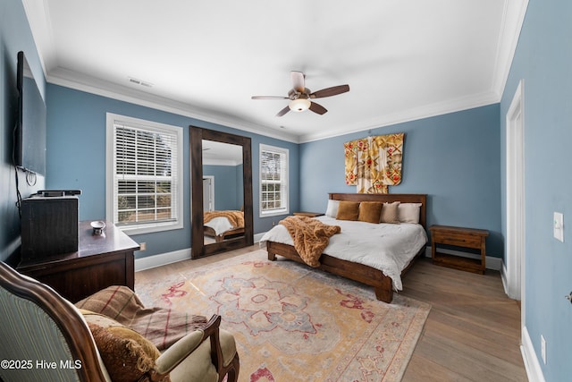 bedroom with visible vents, baseboards, crown molding, and light wood-style floors