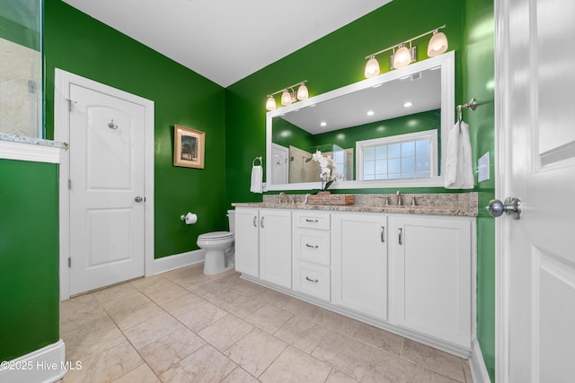 bathroom featuring double vanity, toilet, tiled shower, and a sink