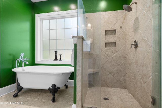 bathroom featuring tile patterned floors, a stall shower, a freestanding bath, and baseboards