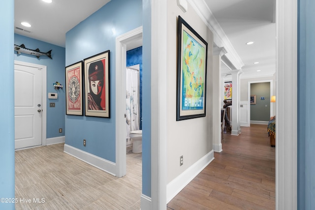 hallway with wood finished floors, visible vents, baseboards, recessed lighting, and crown molding