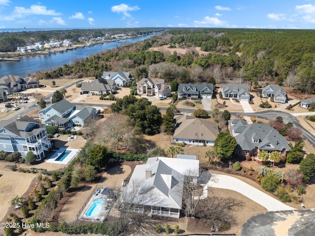 birds eye view of property with a wooded view, a water view, and a residential view