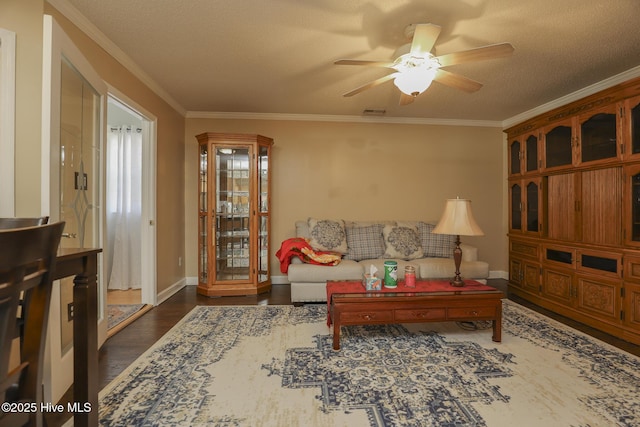 living room featuring baseboards, ceiling fan, ornamental molding, dark wood-style flooring, and a textured ceiling